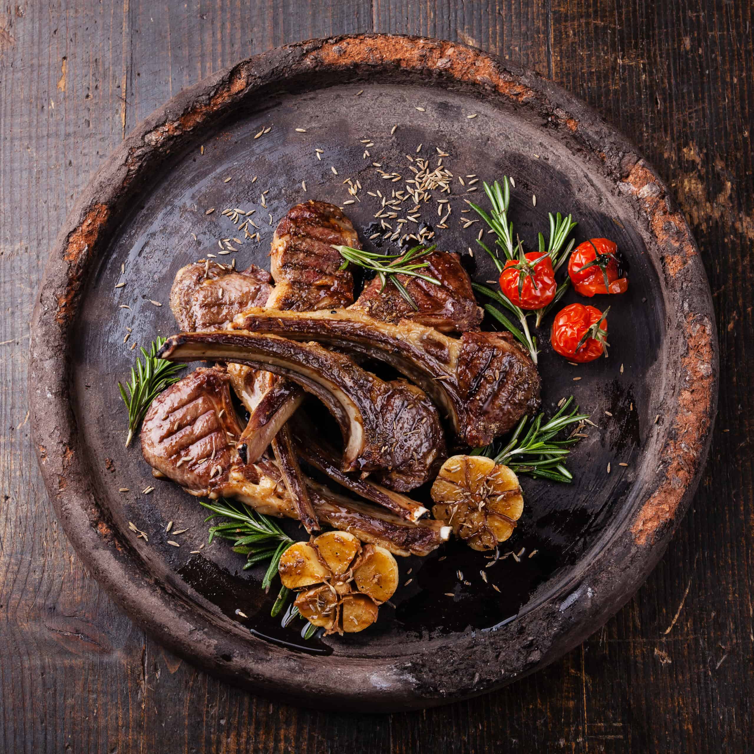 Roasted lamb ribs with spices and garlic on dark textural backgr